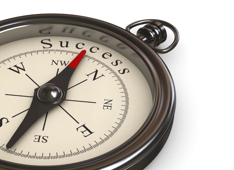A compass whose needle points to the word Success on the dial