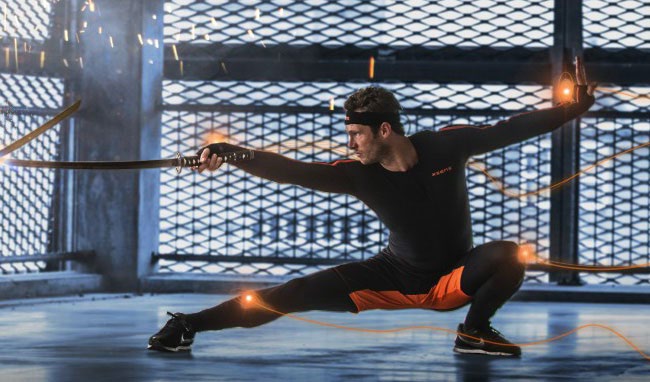 An athlete in a Movella sensor suit lunging with a sword, sensor paths traced in light