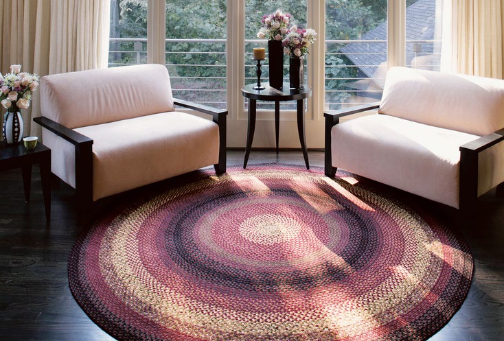 Un grand tapis rond tressé dans un salon lumineux entre deux fauteuils