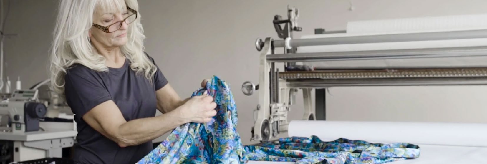 Une femme étale un tissu imprimé sur une table de coupe dans l’atelier Derek Rose