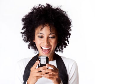 A woman smiling at a mobile phone held in both hands