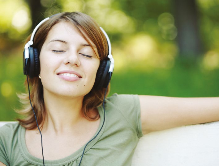 Una mujer al aire libre con auriculares y los ojos cerrados