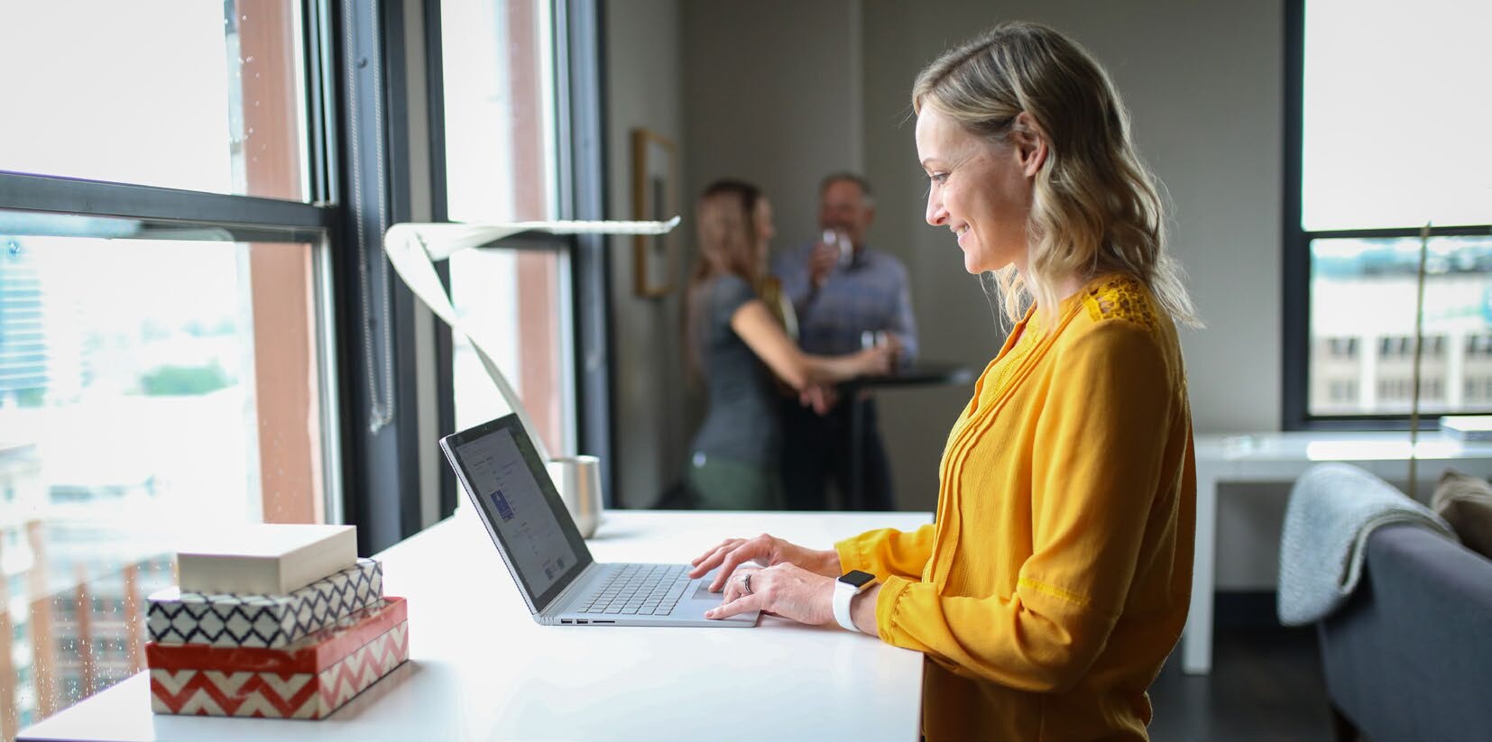 Une femme travaille debout à son ordinateur portable dans un bureau ouvert