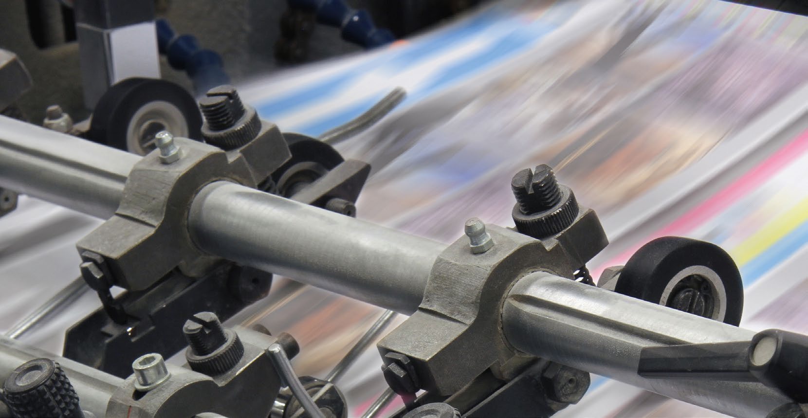 Close-up of press rollers running over freshly printed colour sheets