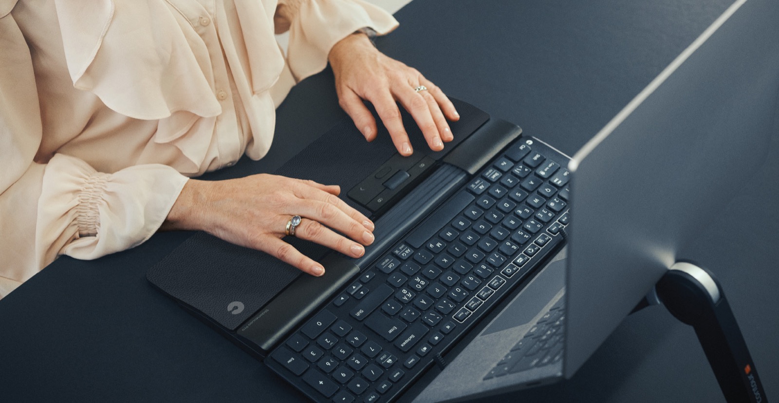 Hände auf einer ergonomischen Tastatur mit Rollstab