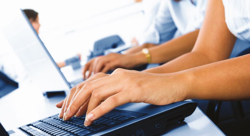Una fila de personas trabajando codo con codo en portátiles
