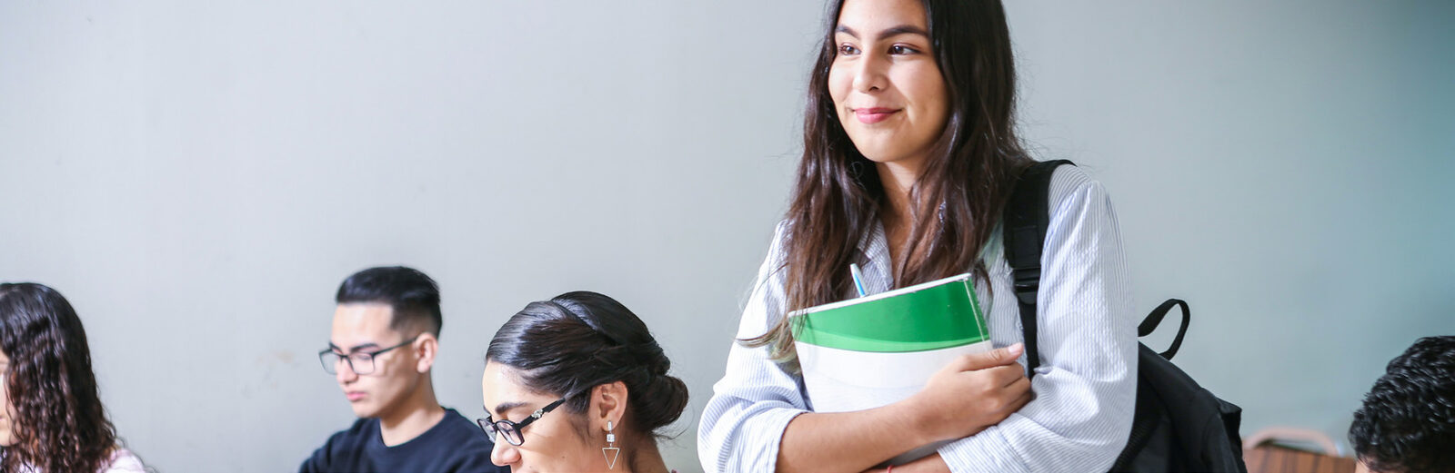 Una alumna con cuadernos en brazos entre un grupo de participantes del curso
