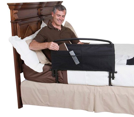 A man sitting up in bed beside a bed rail fitted with a storage pocket