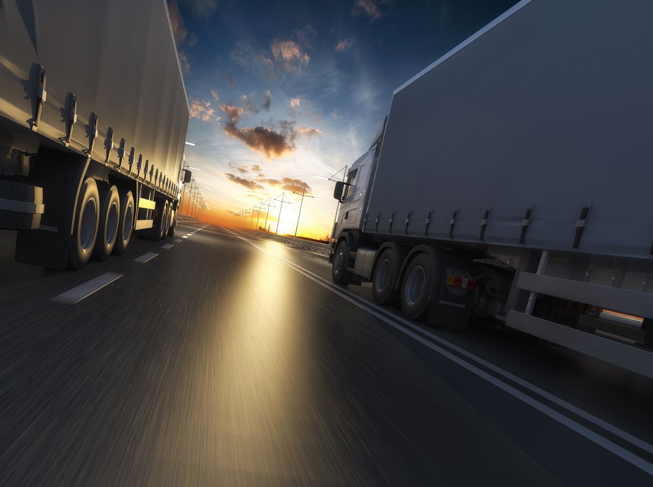 Two lorries passing on a road at dusk, motion blurred