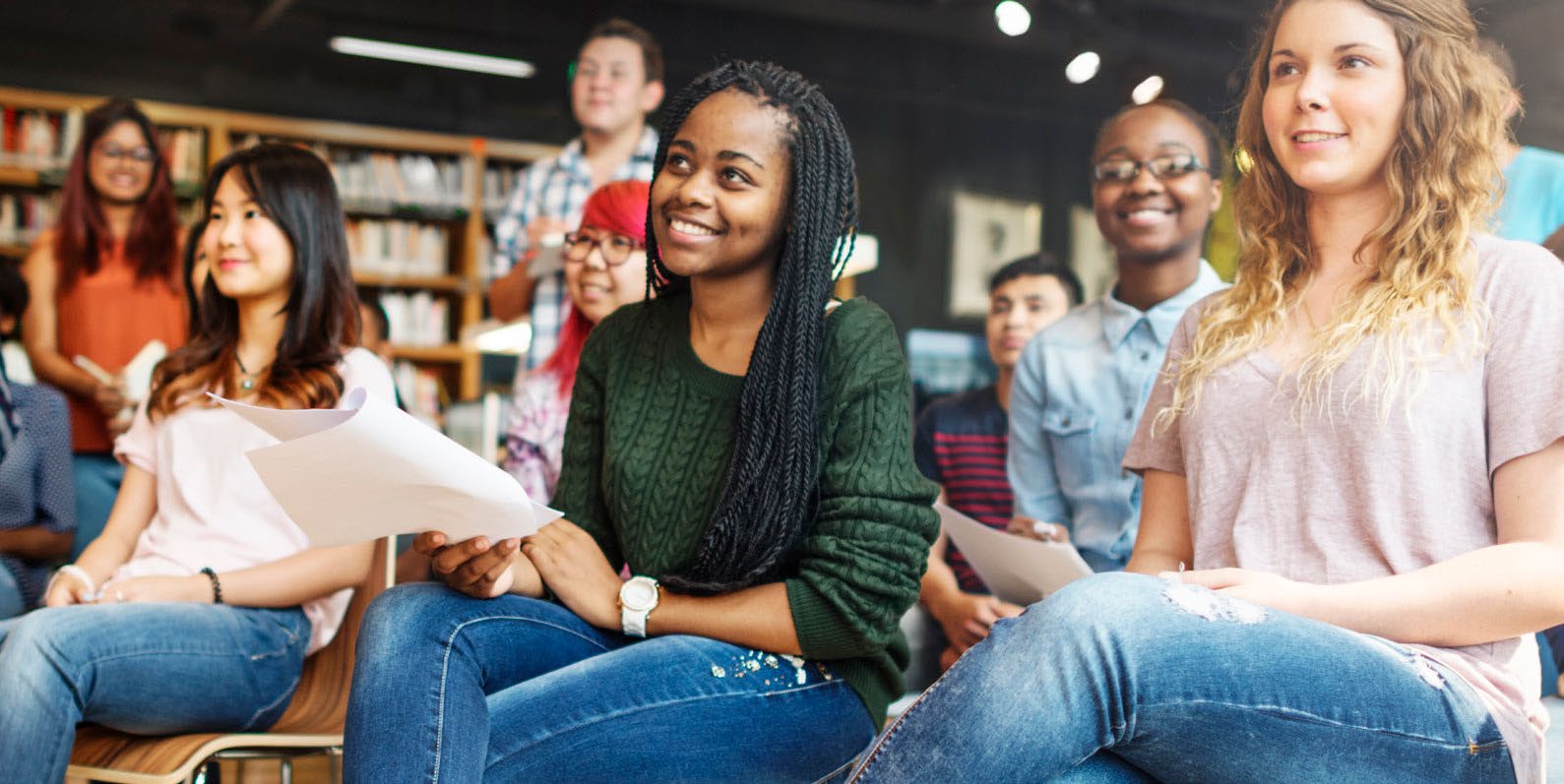 A group of students sitting together in a library, smiling