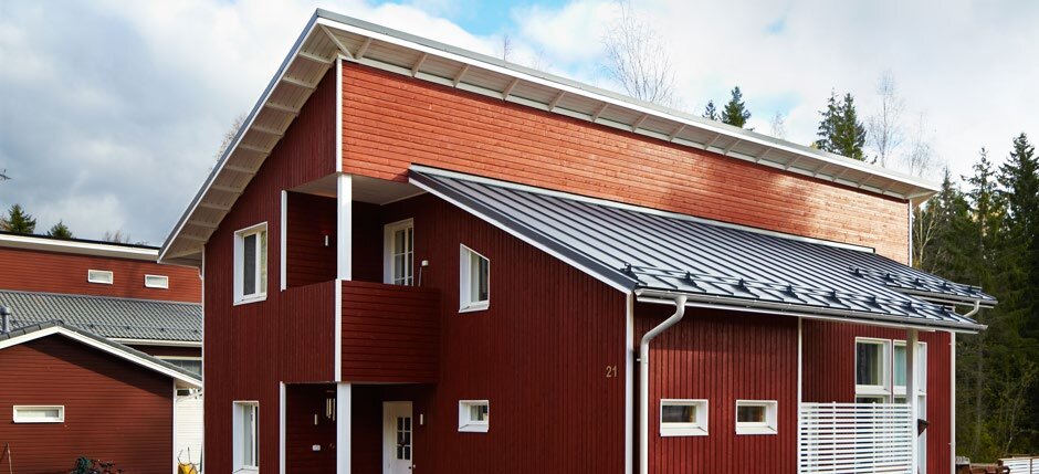 Maisons à bardage de bois rouge avec toitures et gouttières en acier gris Lindab